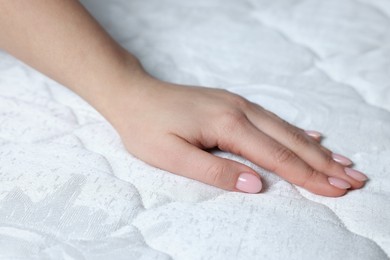 Photo of Woman touching soft white mattress, closeup view