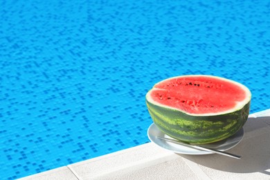 Photo of Half of fresh juicy watermelon on plate near swimming pool outdoors. Space for text