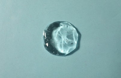 Sample of transparent cosmetic gel on light blue background, top view