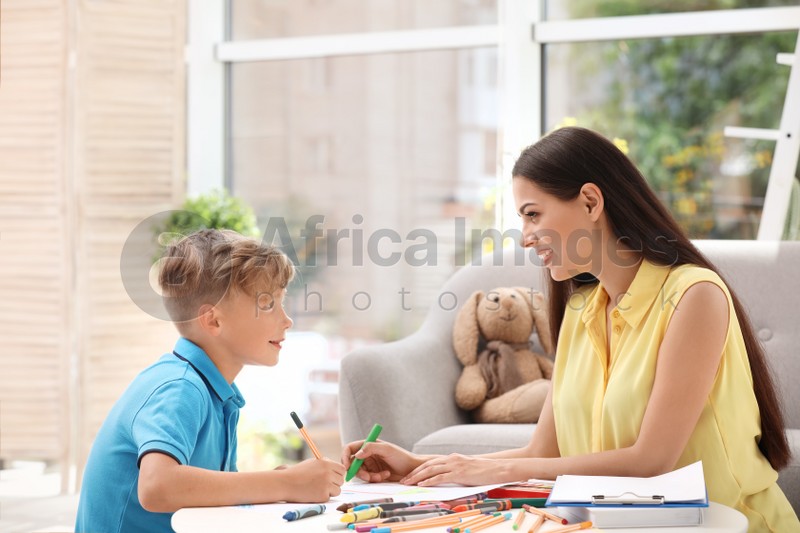 Young female psychologist working with little child in office