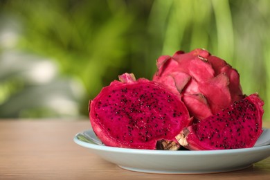 Delicious cut and whole dragon fruits (pitahaya) on wooden table. Space for text