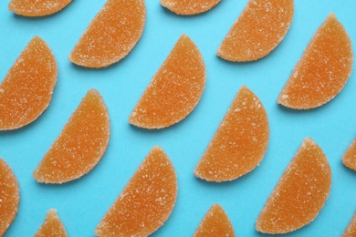 Delicious orange marmalade candies on light blue background, flat lay