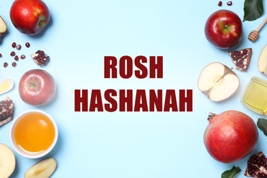 Honey, apples and pomegranates on light blue background, flat lay. Rosh Hashanah holiday