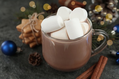 Delicious cocoa drink with marshmallows and Christmas decor on grey table, closeup