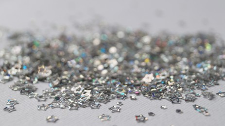 Pile of silver star shaped sequins on white background, closeup