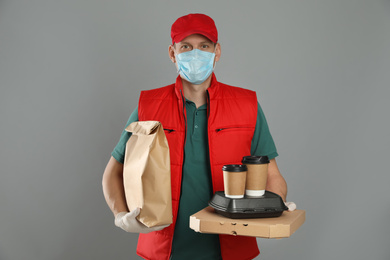Courier in protective mask and gloves holding order on light grey background. Food delivery service during coronavirus quarantine