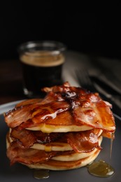 Delicious pancakes with maple syrup and fried bacon on plate, closeup