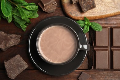 Cup of delicious hot cocoa, chocolate chunks and fresh mint on wooden table, flat lay