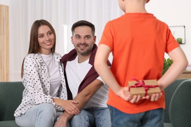 Photo of Little boy presenting his parents with gift at home