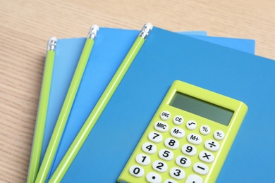Calculator, notebooks and pencils on wooden table, closeup. Tax accounting