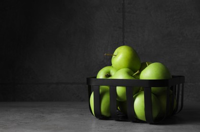 Black metal container full of apples on table against dark grey background, space for text
