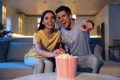 Couple watching movie with popcorn on sofa at night