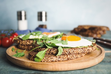 Delicious sandwiches with arugula and fried egg on blue wooden table