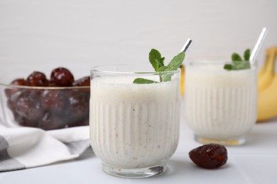 Photo of Glasses of delicious date smoothie with mint on white table