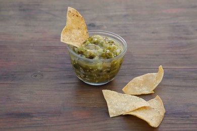 Photo of Tasty salsa sauce and tortilla chips on wooden table