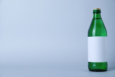 Glass bottle with soda water on light background. Space for text