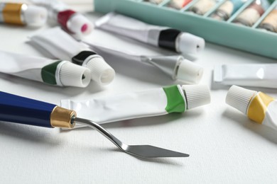Tubes with paints and spatula on blank canvas, closeup