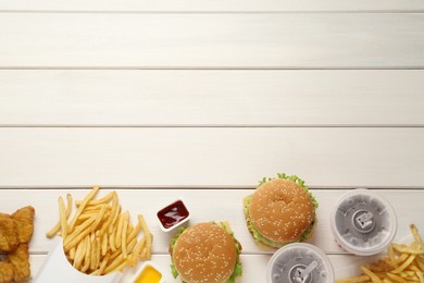 Flat lay composition with delicious fast food menu on white wooden table. Space for text