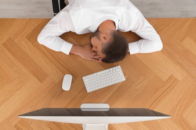 Photo of Tired man sleeping at workplace, top view