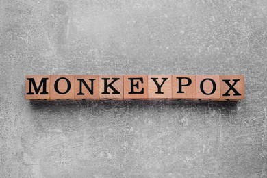 Word Monkeypox made of wooden cubes on light grey background, top view
