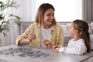 Woman and his little daughter playing with puzzles at home