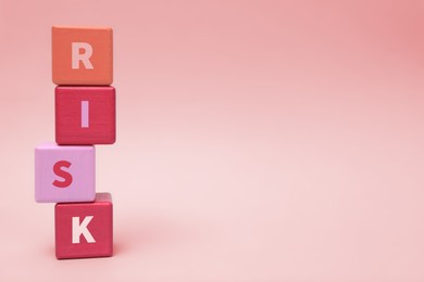 Stack of color wooden cubes with word Risk on light grey background. Space for text