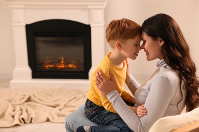Photo of Happy mother and son spending time together near fireplace at home