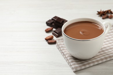 Photo of Yummy hot chocolate in cup on white wooden table. Space for text