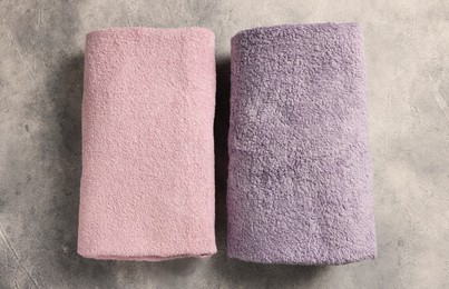 Photo of Soft folded terry towels on light gray textured background, flat lay