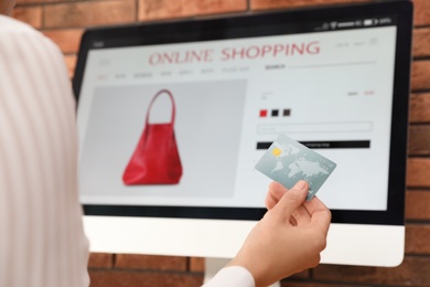 Woman with credit card using computer for online shopping indoors, closeup