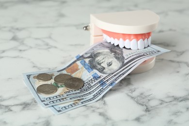 Educational dental typodont model and money on white marble table. Expensive treatment