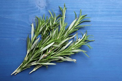Sprigs of fresh rosemary on blue wooden table, top view