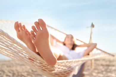 Young woman relaxing in hammock outdoors, focus on legs