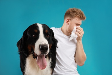 Photo of Young man suffering from fur allergy on blue background