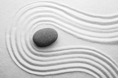 Grey stone on sand with pattern, top view. Zen, meditation, harmony