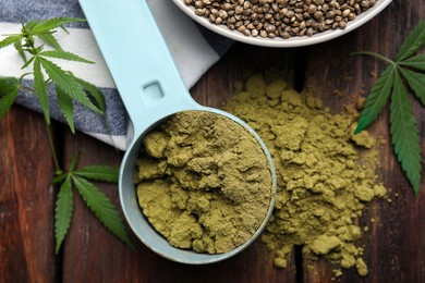 Hemp protein powder and fresh leaves on wooden table, flat lay