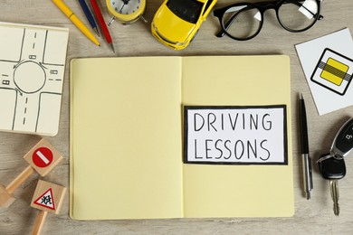 Flat lay composition with workbook for driving lessons and road signs  on wooden background. Passing license exam
