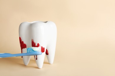 Tooth model, brush and blood in toothpaste foam on beige background, space for text. Gum problems