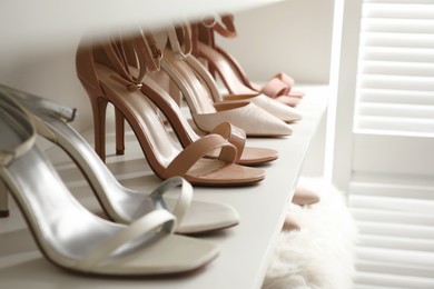 Different stylish women's shoes on shelf in dressing room, closeup