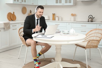 Businessman in underwear pretending to wear formal clothes during video call at home