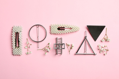 Stylish hair clips and flowers on pink background, flat lay