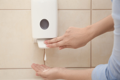 Woman applying antiseptic soap onto hand in bathroom, closeup. Virus prevention