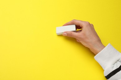 Woman erasing something on yellow background, closeup. Space for text