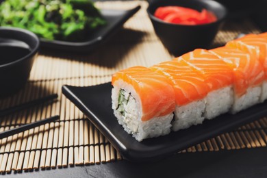 Tasty sushi rolls served on black table, closeup