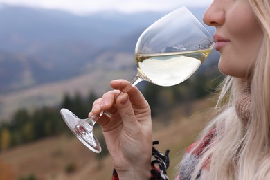 Young woman drinking wine in peaceful mountains, closeup
