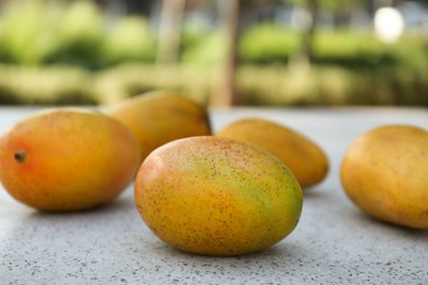 Delicious ripe juicy mangos on table outdoors, closeup
