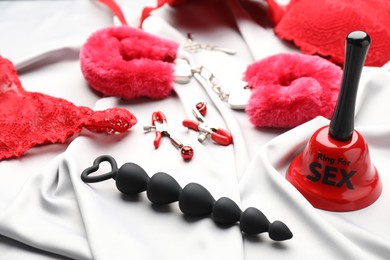 Photo of Sex toys and accessories on white fabric