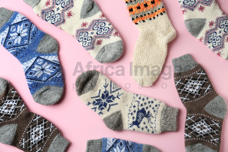 Different knitted socks on pink background, flat lay. Winter clothes