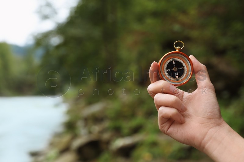 Traveler searching direction with compass in wilderness, closeup. Space for text
