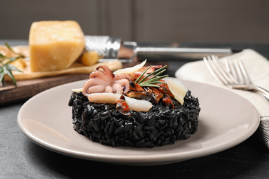 Photo of Delicious black risotto with seafood on grey table